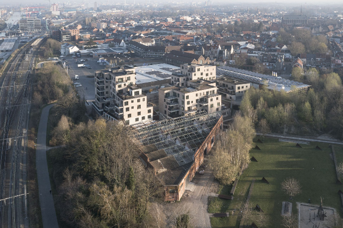 Luchtfoto van Bijgaardehof en Bijgaardepark in Gent met driehoekige fabriekshal, cohousingproject en aangrenzend openbaar groen nabij het spoor.