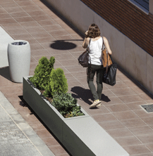Moderne stoep met een lange strakke plantenbak en aansluitende zitbank tussen gevel en rijweg die voetgangers beschermt en de openbare ruimte vergroent.