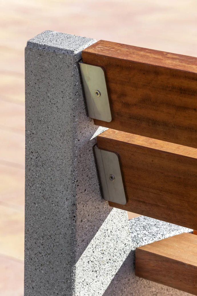 Close-up Alpine buitenbank: houten zit- en ruglatten op betonnen steun, sobere afwerking voor park en openbare ruimte