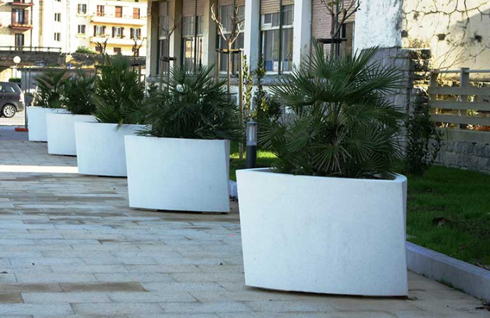 Bilbao plantenbakken van Escofet 1886 in wit gewapend beton langs een stedelijke wandelzone, gevuld met palmachtige beplanting voor groene straatinrichting.