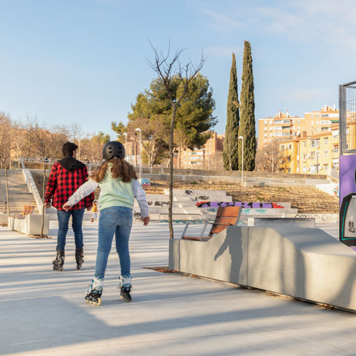 Garonne zitbanken van Escofet 1886 in licht beton langs een stedelijke skate- en speelzone, met modulaire rugloze zitelementen en houten rugleuning als rustpunt voor skaters en parkgebruikers.