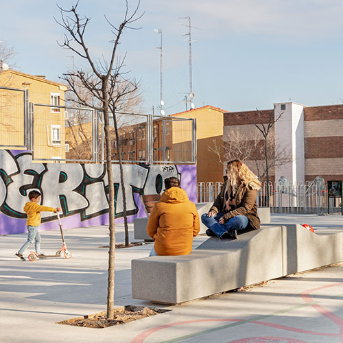 Garonne modulaire betonnen zitbanken van Escofet 1886 op een stedelijk plein, gebruikt door kinderen en volwassenen als robuuste rugloze zitelementen voor spelen, zitten en ontmoeting.