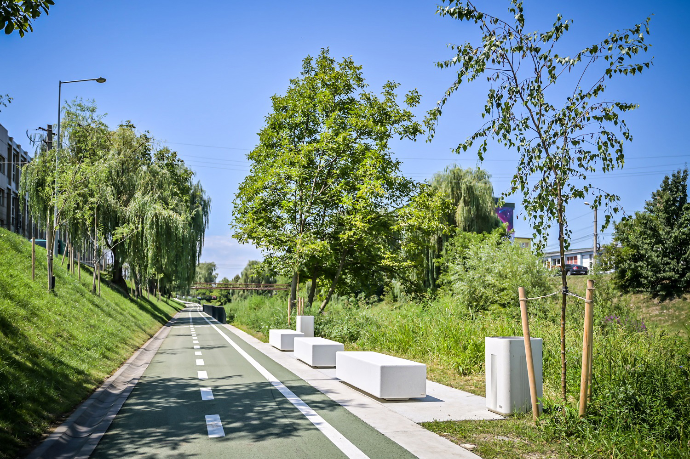 Witte Garonne zitbanken van Escofet 1886 langs een groene fietspromenade, geplaatst als modulaire betonnen rustpunten tussen bomen en landschappelijke beplanting.